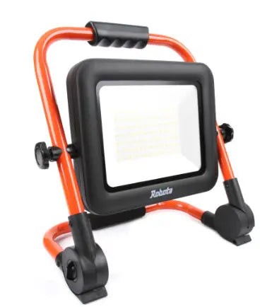 Oranssi-musta 18V akkutyövalaisin säädettävällä jalustalla tuo valoa.