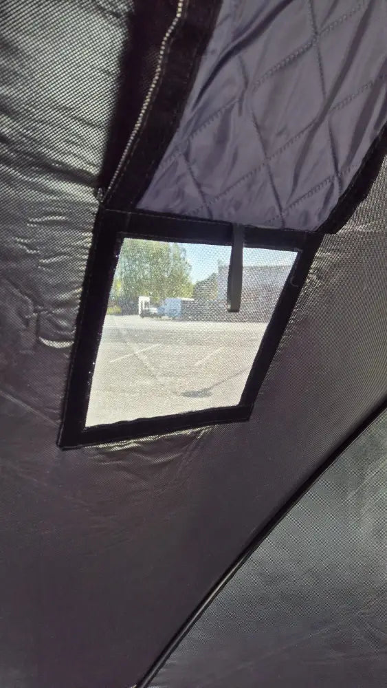 Black mesh window with reinforced black frame set into dark gray quilted fabric of väinö sauna box pop up saunateltta